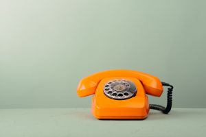 Telefon stacjonarny w kolorze pomarańczowym na zielonym tle